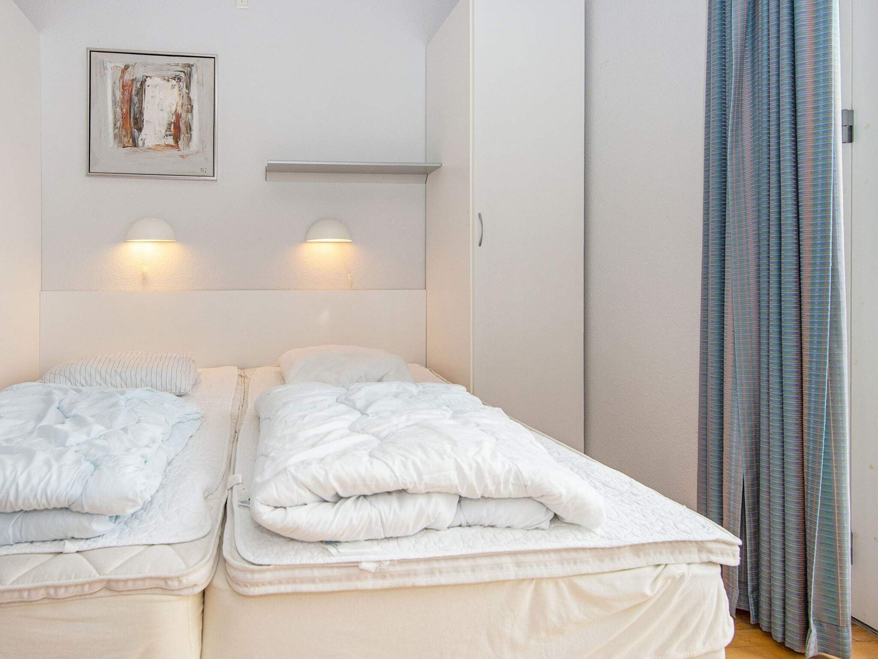 Una habitación de hotel con dos camas, un cuadro en la pared y una ventana con cortinas.