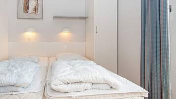 Una habitación de hotel con dos camas, un cuadro en la pared y una ventana con cortinas.