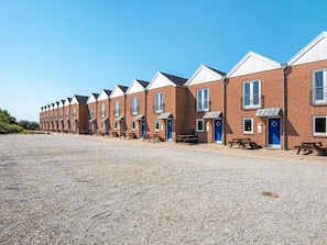 A row of brick buildings with blue doors and windows, each with a small patio area. - 6 Person Holiday Home in Hojer (Højer)