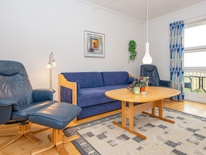 A modern living room with a blue sofa, two blue chairs, a wooden coffee table, a floor lamp, and a potted plant. - 6 Person Holiday Home in Hojer (Højer)