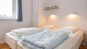 Ein Schlafzimmer mit einem Bett, einem Kleiderschrank, einem Fenster mit Vorhängen und Wandleuchten.