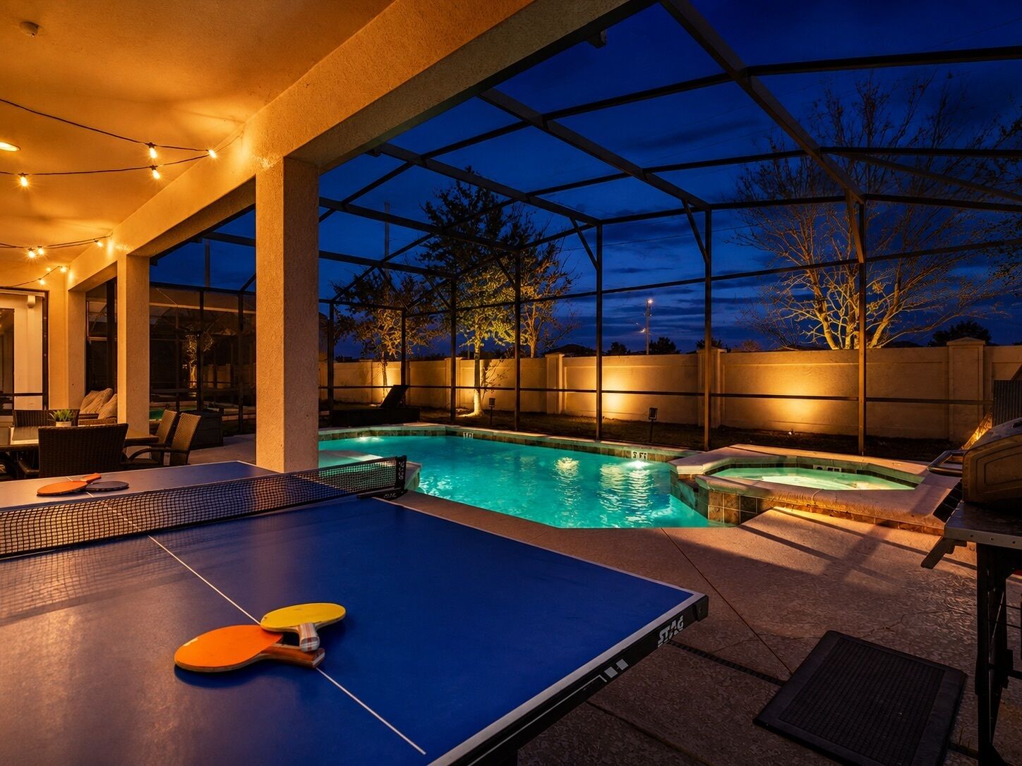 Un espace piscine équipé d’une table de ping-pong, d’un jacuzzi et de coins salon extérieurs.