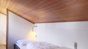 A bedroom with a bed, a bedside table, a lamp, and a wooden ceiling. - 5 Person Holiday Home in Vaeggerlose (Vaeggerlose)
