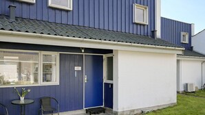 A residential building with a blue exterior, a white door, and a small outdoor seating area with two chairs and a table. - 5 Person Holiday Home in Vaeggerlose (Vaeggerlose)