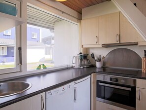 A compact kitchen with a built-in dishwasher, a coffee maker, and a stove. - 5 Person Holiday Home in Vaeggerlose (Vaeggerlose)