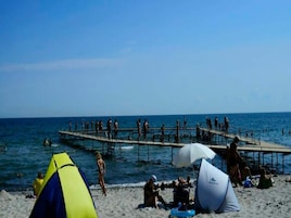 A beach with a pier, tents, and people.