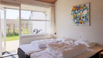 A room with a bed, a window, and a painting on the wall.