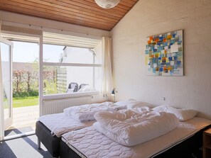 A room with a bed, a window, and a painting on the wall.