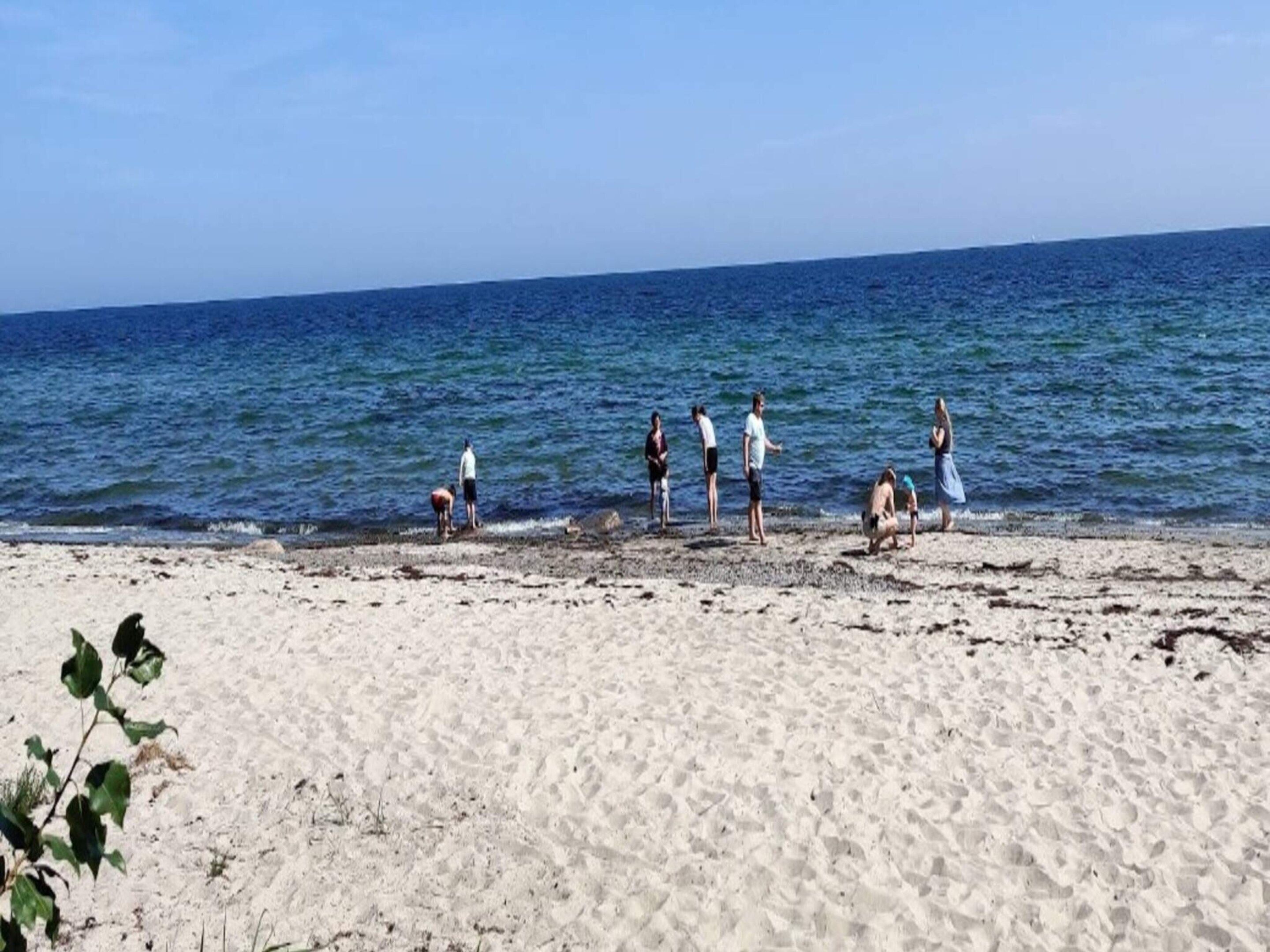 A beach with people standing and walking along the shore.