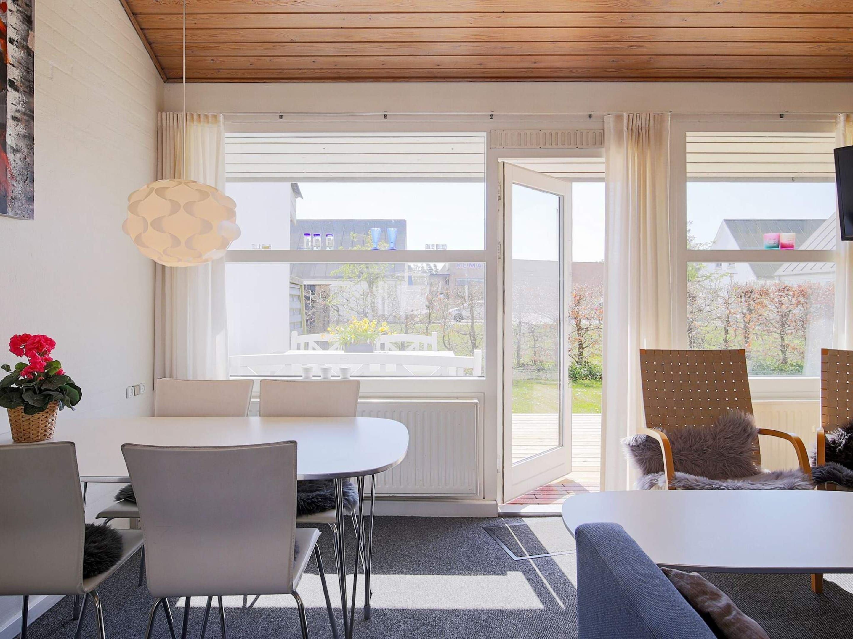 Un salon moderne avec un coin repas, de grandes fenêtres et une vue sur l’extérieur.