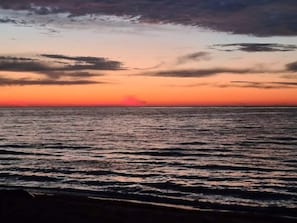 A sunset over a body of water with a clear horizon.