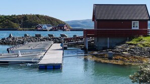 A pier extending into calm waters with boats docked, a small red building, and houses in the background. - 6 Person Holiday Home in Brekstad (Orland)