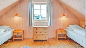 A cozy attic bedroom with wooden walls and a sloped ceiling. It features two single beds, a wooden dresser, and a window with curtains. - 6 Person Holiday Home in Brekstad (Orland)