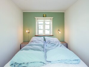 A single bed with a white mattress and two pillows, a window with a white frame, and two wall-mounted light fixtures. - 5 Person Holiday Home in Oster Assels (Øster Assels)