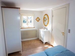 Een kamer met een bed, een dressoir, een radiator en een raam.