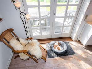 A room with a wooden chair, a fluffy rug, a dog bed, and a lamp. - 5 Person Holiday Home in Oster Assels (Øster Assels)