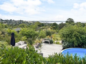 A residential outdoor area with a swimming pool, a wooden deck, and a view of a distant landscape. - 4 Star Holiday Home in Ebeltoft (Ebeltoft)