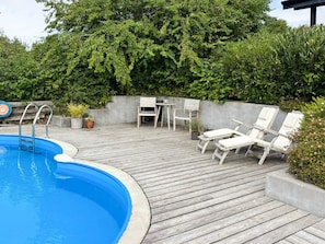 A wooden deck with a swimming pool, lounge chairs, and a table. - 4 Star Holiday Home in Ebeltoft (Ebeltoft)