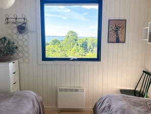 A room with a large window, a white radiator, a plant, and a framed picture on the wall. - 4 Star Holiday Home in Ebeltoft (Ebeltoft)