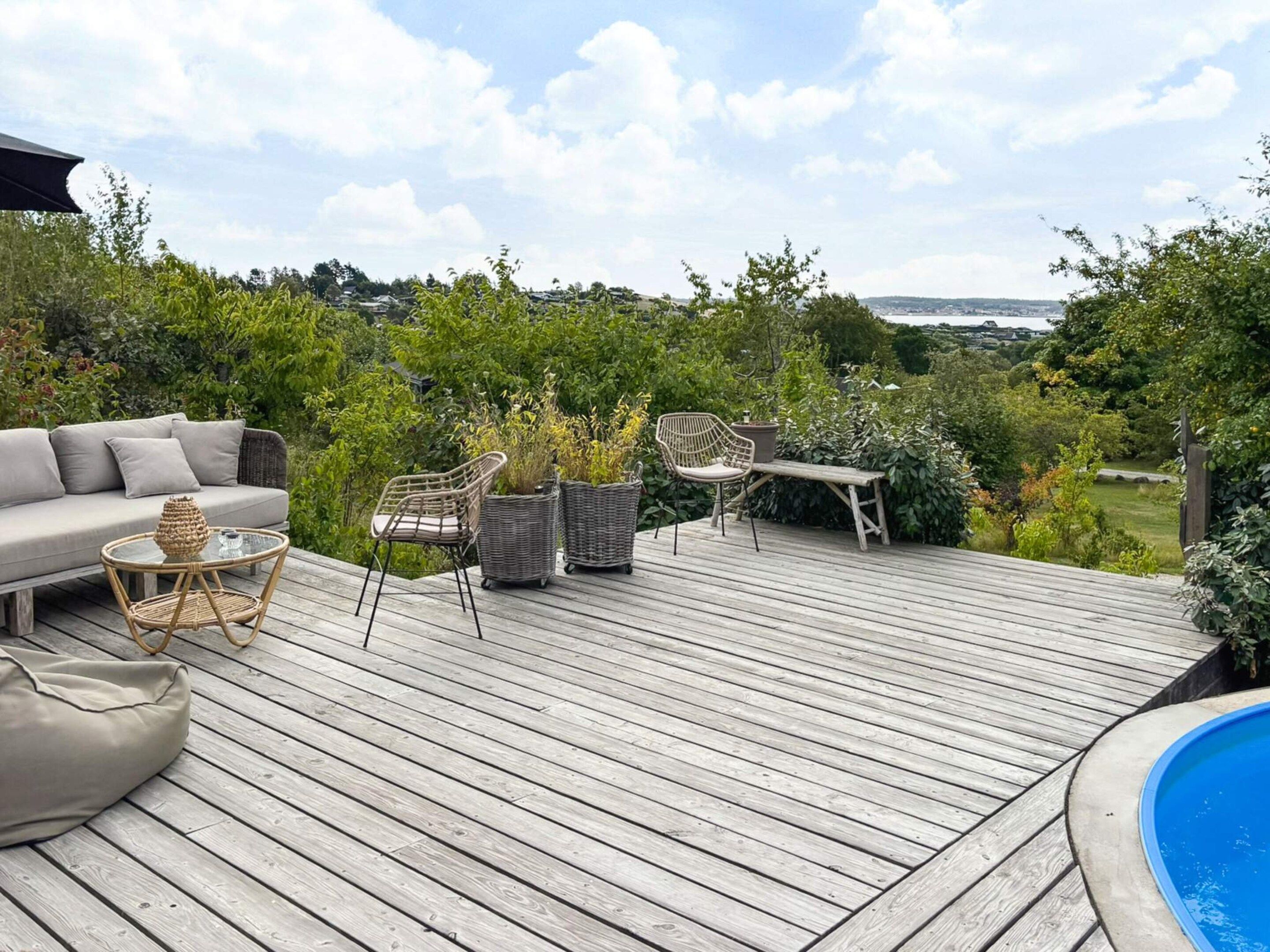 A wooden deck with outdoor furniture, a pool, and a view of the countryside.
