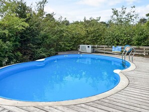 A clear blue swimming pool with a wooden deck surrounding it, a metal ladder, and an air conditioning unit in the background. - 4 Star Holiday Home in Ebeltoft (Ebeltoft)
