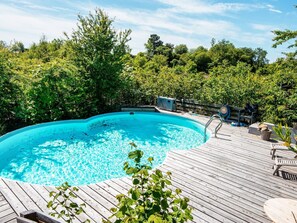 A swimming pool with a wooden deck, surrounded by lush greenery. - 4 Star Holiday Home in Ebeltoft (Ebeltoft)