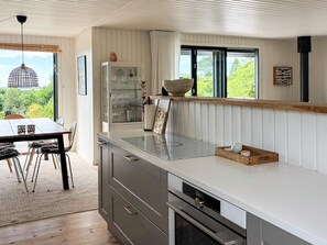 A modern kitchen with a dining area, large windows, and a view of greenery. - 4 Star Holiday Home in Ebeltoft (Ebeltoft)