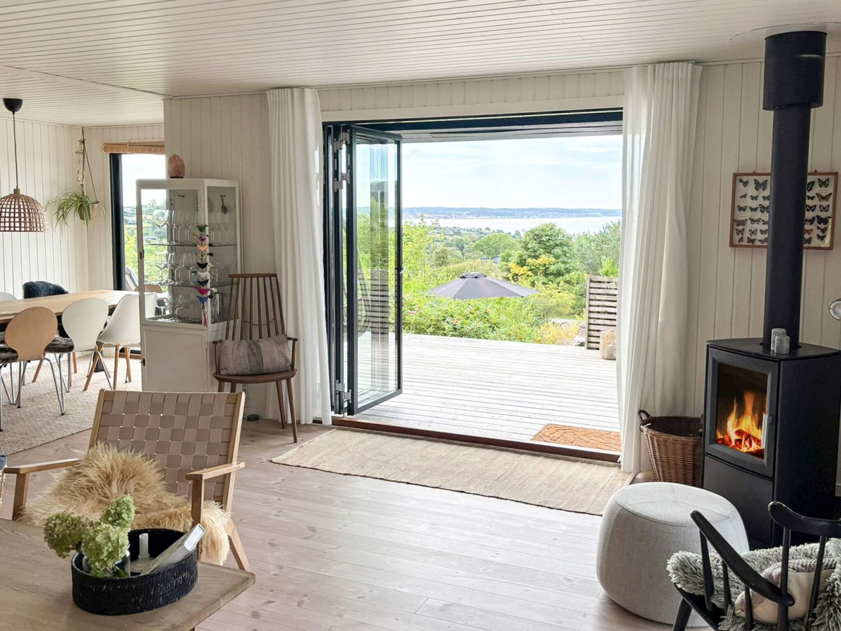 A modern living room with a fireplace, a dining area, and a view of the outdoors.