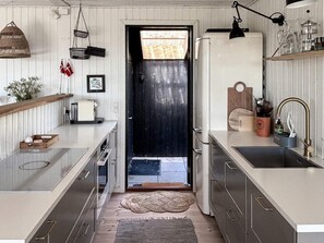A modern kitchen with a black door, stainless steel appliances, and a wooden countertop. - 4 Star Holiday Home in Ebeltoft (Ebeltoft)