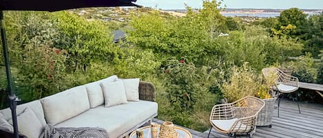 Une terrasse dotée d’un canapé, de chaises et d’une table, offrant une vue sur un paysage luxuriant.
