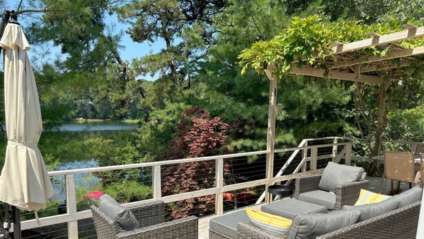 Une terrasse dotée de meubles en osier, d’une table et d’un parasol.