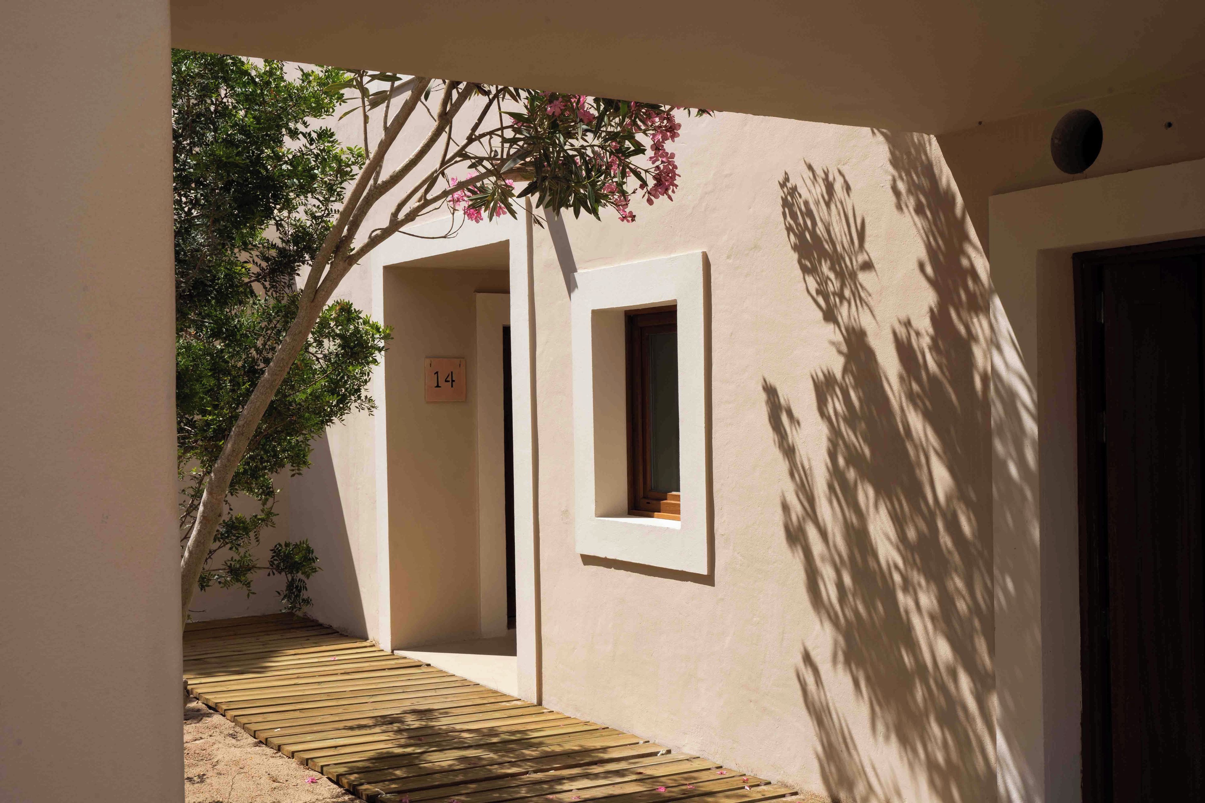 Un estrecho sendero de madera que conduce a un edificio con un cartel con el número 14, una ventana y una puerta.