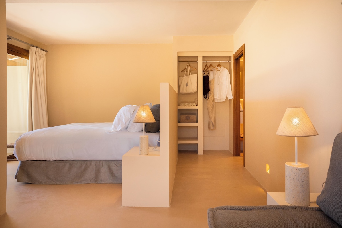 Une chambre à coucher comprenant un lit, des lampes de chevet, une armoire et un coin salon.