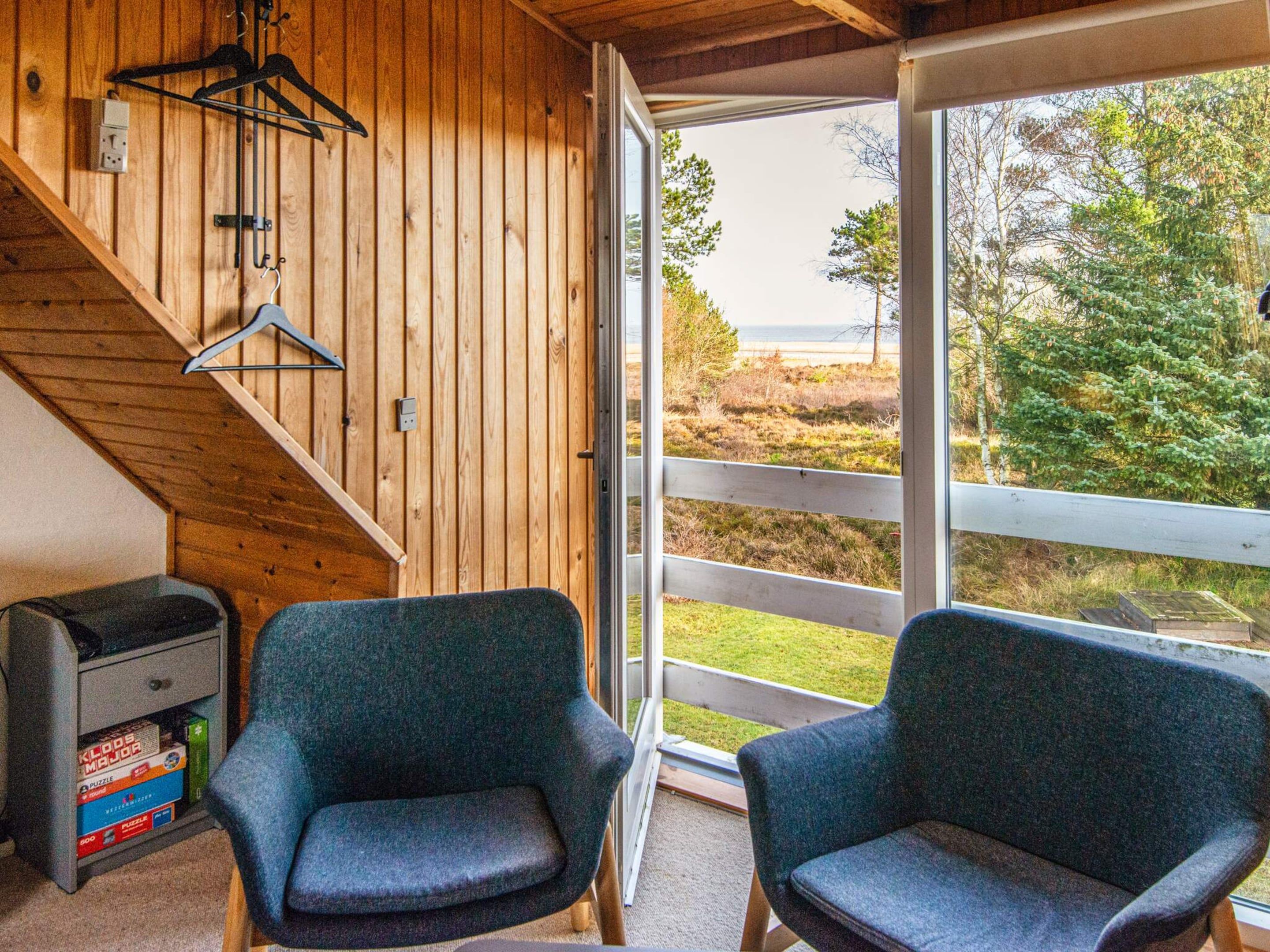 A wooden interior with two chairs, a puzzle box, and a view of the outdoors.