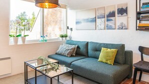 A cozy living room with a sofa, a glass coffee table, and a bookshelf.