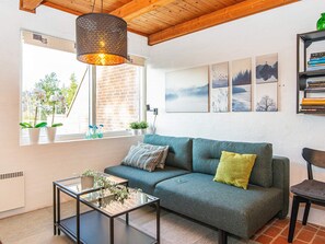 A cozy living room with a sofa, a glass coffee table, and a bookshelf.