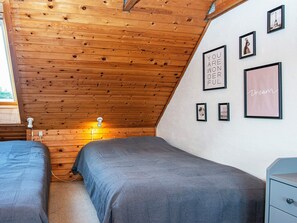 A bedroom with two beds, wooden ceiling, and wall-mounted pictures. - 5 Person Holiday Home in Romo (Rømø)