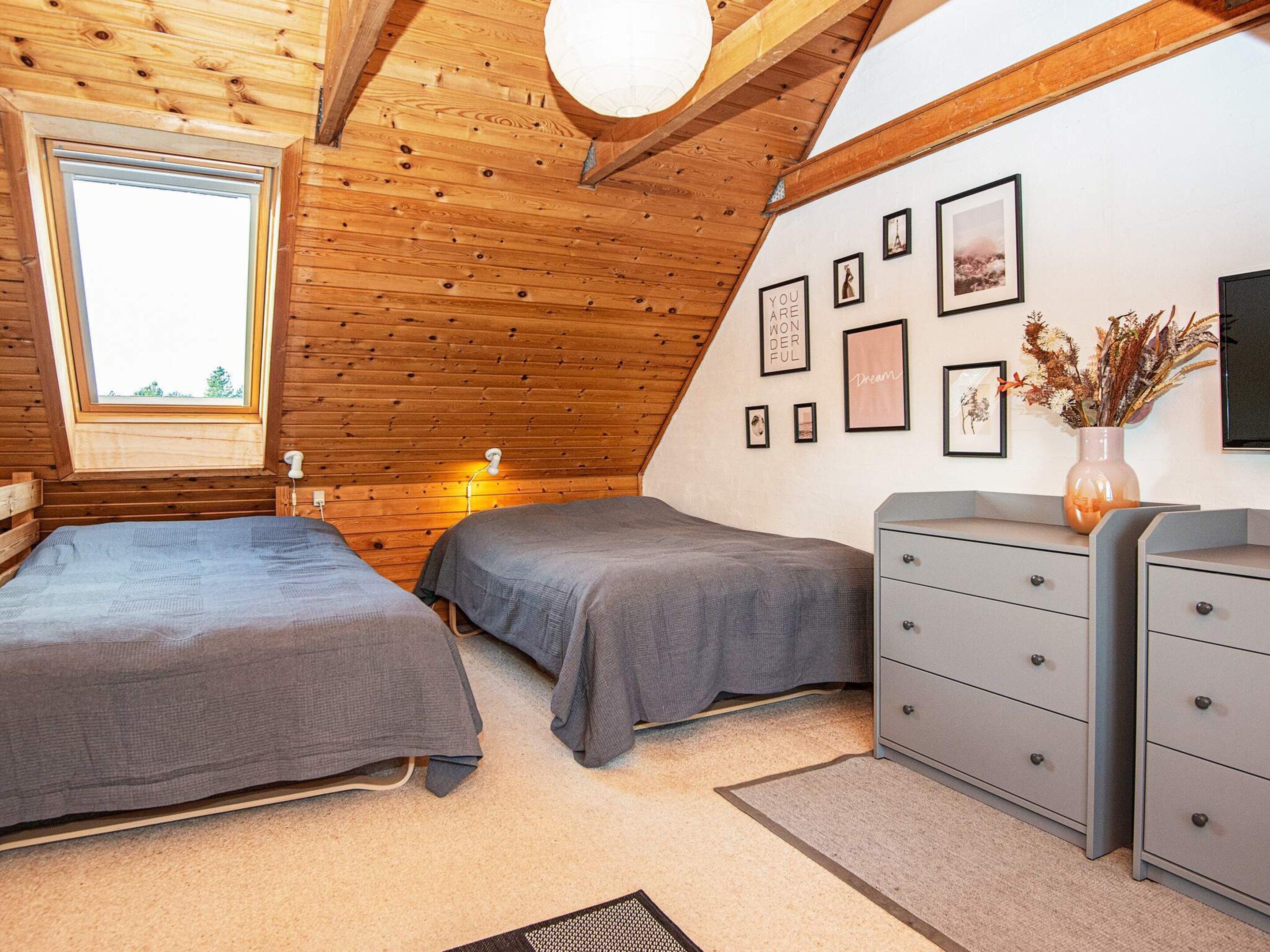 A bedroom with two beds, a dresser, a window, and wall decorations.