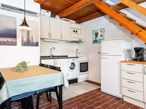 Compact kitchen with a washing machine, coffee maker, and table for dining.