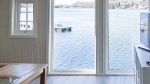 Une pièce dotée d’une grande fenêtre donnant sur une étendue d’eau, d’un banc en bois et d’un tapis à motifs.