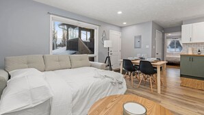 Une pièce moderne et bien éclairée, dotée d’un grand lit, d’une table à manger avec des chaises et d’un coin cuisine.
