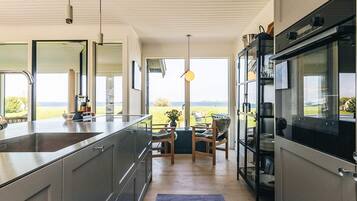 Una cocina moderna con una isla grande, electrodomésticos integrados y vistas al exterior.