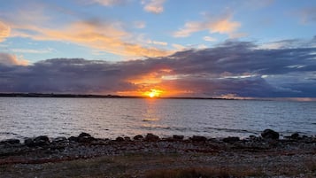 A sunset over a body of water with a rocky shoreline.