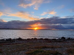 Ein Sonnenuntergang über einem Gewässer mit einer felsigen Küste.