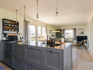 Eine moderne Küche mit einer großen Kücheninsel, eingebauten Schränken und Pendelleuchten.