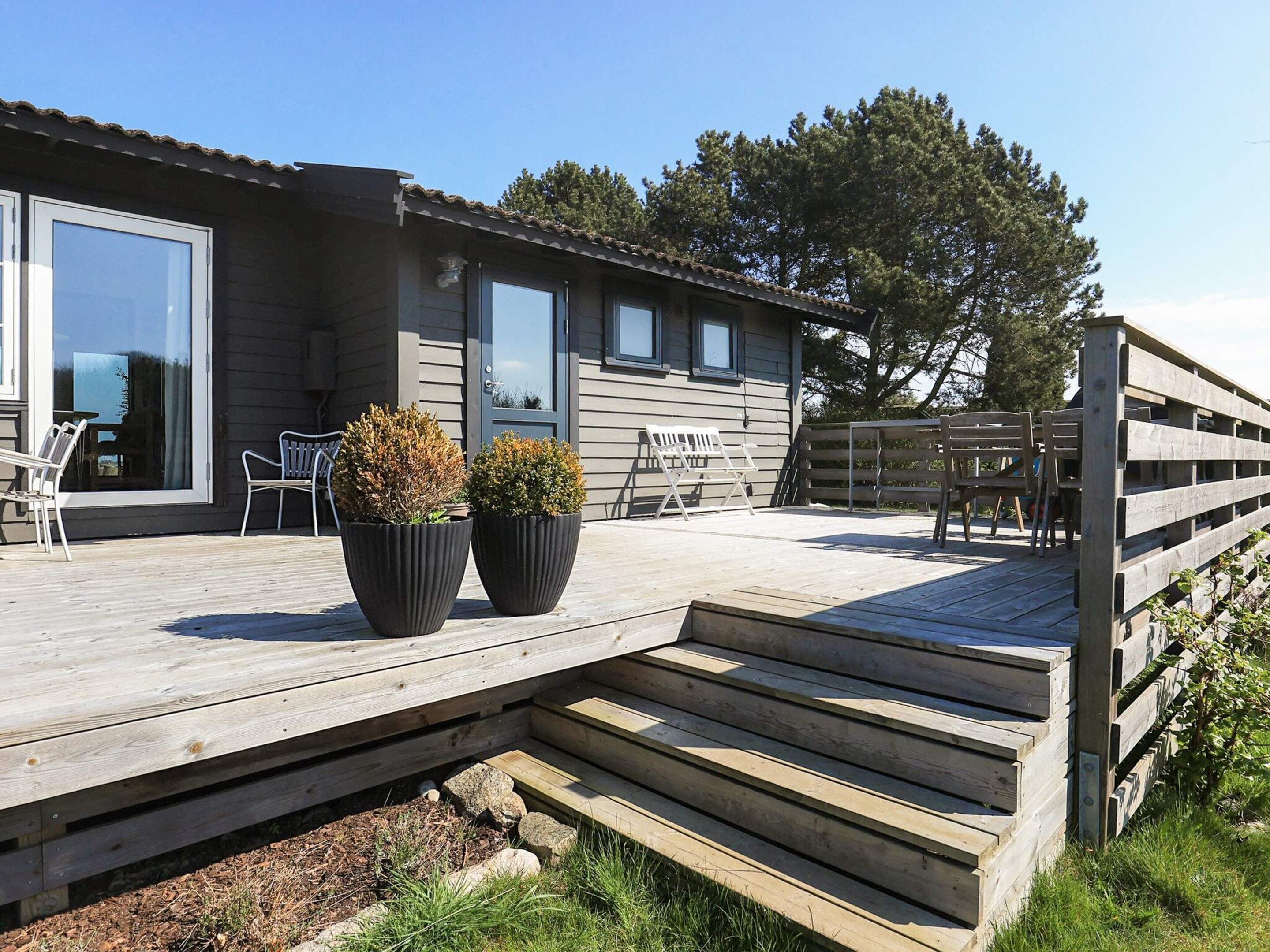 A wooden deck with outdoor seating, a building with large windows, and a wooden fence.