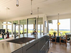 A modern kitchen with a large island, stainless steel appliances, and a view of the outdoors.
