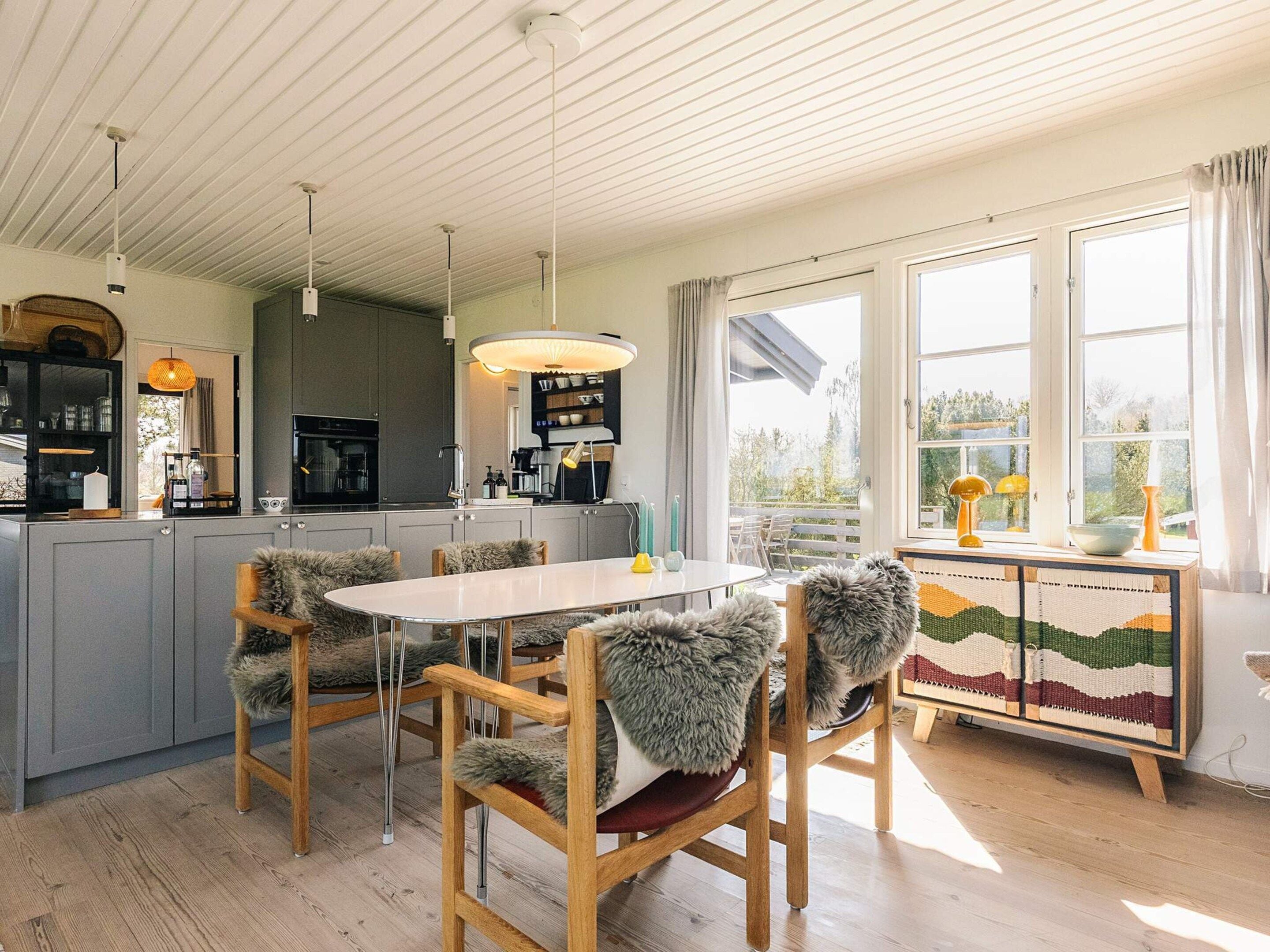 A modern kitchen with grey cabinets, a central island, and a dining area with a round table and chairs.