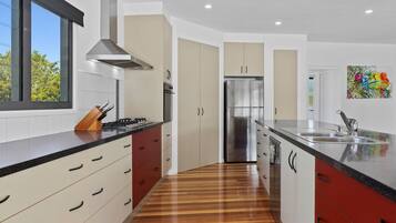 A modern kitchen with a gas stove, stainless steel appliances, and a wooden floor.
