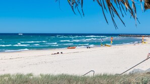 Une plage offrant une vue dégagée sur l’océan, une tour de surveillance des sauveteurs et une planche de surf.